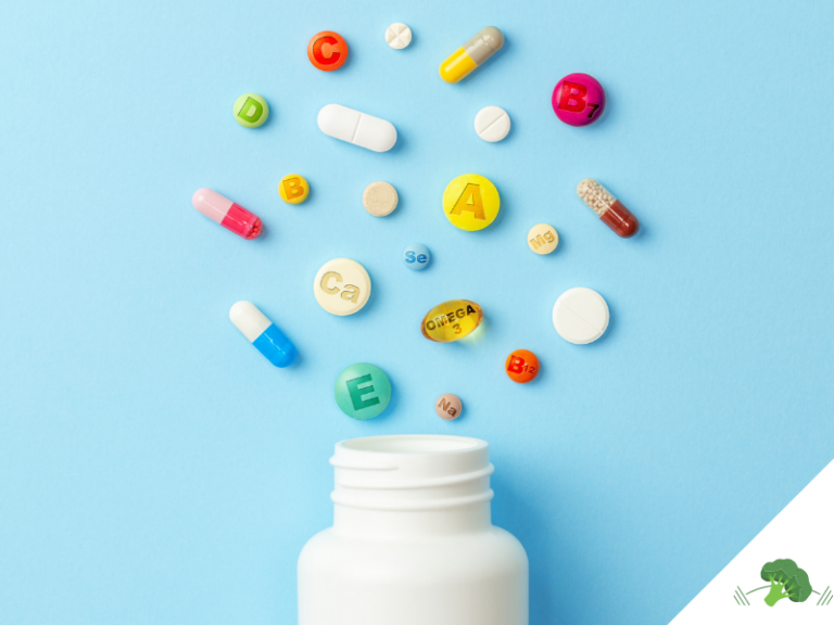 Eine offene weiße Pillendose vor einem blauen Hintergrund, aus der farbenfrohe Tabletten, Kapseln und Mikronährstoffe "herausfliegen". Auf den Pillen sind Symbole für Vitamine und Mineralstoffe wie A, B, C, D, E, Omega-3, Calcium (Ca), Magnesium (Mg) und Selen (Se) zu sehen. Die Szene repräsentiert die Bedeutung von Nahrungsergänzungsmitteln und Mikronährstoffen. In der unteren rechten Ecke befindet sich das Logo von **"Vegane Sporternährung für alle" by Anne Mayer**, dargestellt durch ein grünes Brokkoli-Icon.