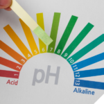 Eine pH-Skala mit den Bereichen von sauer (rot) bis alkalisch (blau) und einem Teststreifen, der den leicht basischen Bereich anzeigt.