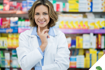 Eine junge Apothekerin steht lächelnd vor einem Regal mit Nahrungsergänzungsmitteln und Gesundheitsprodukten in einer Drogerie oder Apotheke. Sie trägt einen weißen Kittel und wirkt freundlich und kompetent.