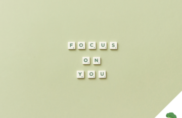 Scrabble-Buchstaben auf einem hellgrünen Hintergrund formen die Worte „FOCUS ON YOU“ in drei Zeilen, unten rechts befindet sich ein freier Bereich mit weißem Dreieck und einer Illustration eines grünen Brokkoli mit Hanteln.