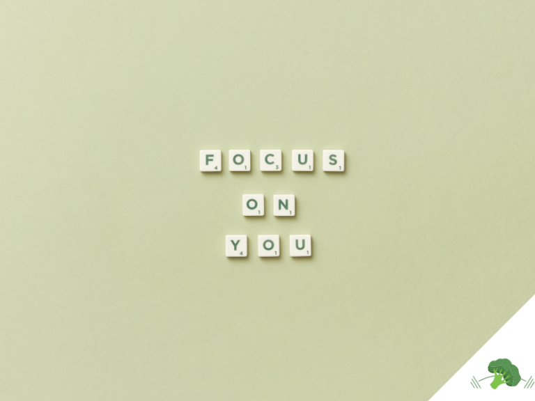 Scrabble-Buchstaben auf einem hellgrünen Hintergrund formen die Worte „FOCUS ON YOU“ in drei Zeilen, unten rechts befindet sich ein freier Bereich mit weißem Dreieck und einer Illustration eines grünen Brokkoli mit Hanteln.