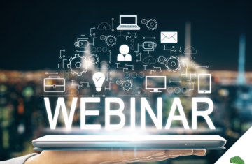 Eine Hand hält ein digitales Tablet, über dem das Wort „WEBINAR“ leuchtend erscheint. Darüber schweben zahlreiche Symbole wie Laptop, Person, E-Mail, Zahnräder und Glühbirne, die digitale Vernetzung und Online-Kommunikation symbolisieren. Im Hintergrund ist eine unscharfe Stadtansicht bei Nacht zu sehen.