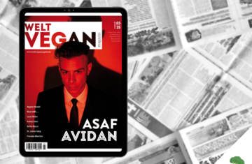 Tablet mit dem Cover der Ausgabe 03|2025 des Welt Vegan Magazins, auf dem der Künstler Asaf Avidan in rotem Licht abgebildet ist, im Hintergrund eine schwarz-weiße Collage aus geöffneten Zeitungsseiten, unten rechts das Logo „Vegane Sporternährung für alle“.