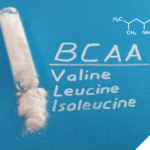 Reagenzglas mit weißem Pulver auf blauem Hintergrund, daneben die Aufschrift BCAA mit den Begriffen Valine, Leucine und Isoleucine sowie die chemische Strukturformel von Leucin oben rechts