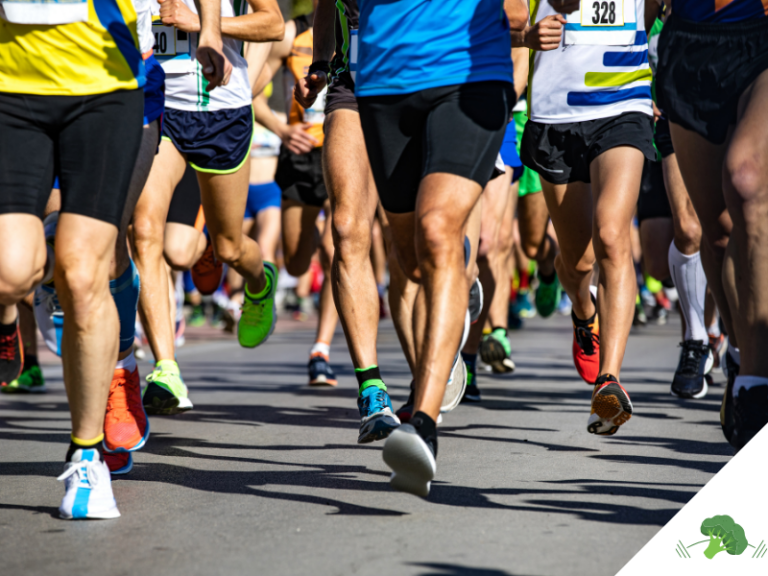 Läuferinnen und Läufer während eines Straßenlaufs in Wettkampfkleidung. Das Bild zeigt zahlreiche Beine und Laufschuhe in Bewegung und verdeutlicht das Thema Lauftraining, Ausdauersport und Laufverletzungen.